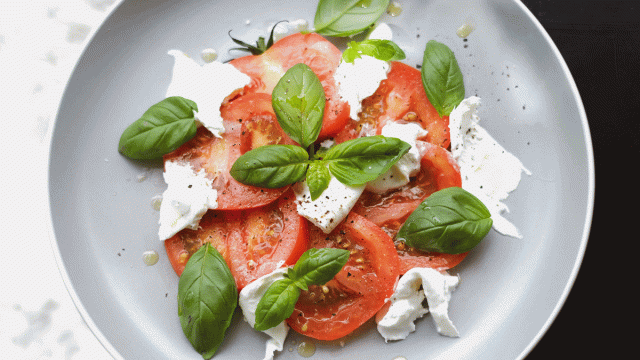 Tomatoes, mozzarella cheese and basil sit on a plate as an easy-to-make Thanksgiving side