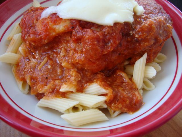 Chicken parm that was made in a crock pot sits on top of pasta on a plate