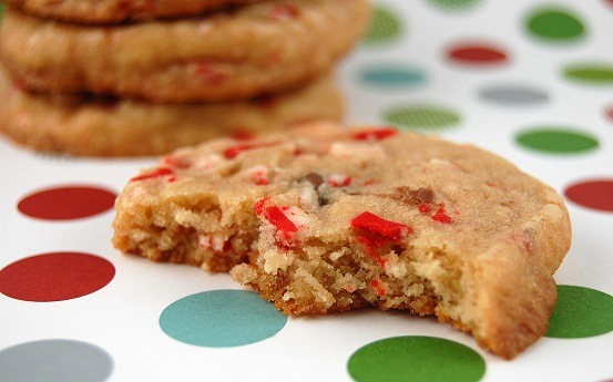 A few bites are taken out of a colorful peppermint chocolate chip cookie that sits on a polka dot tablecloth