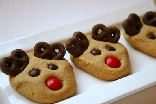 Several Christmas cookies on a plate are shaped and decorated like reindeer