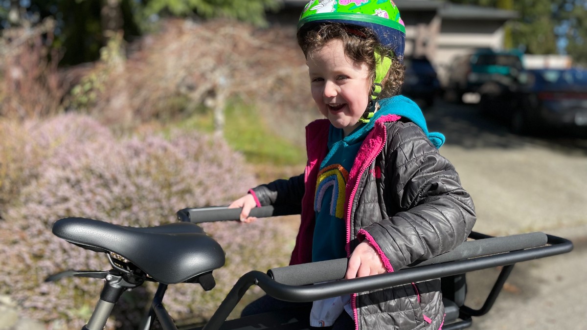 A child sits in the child seat on an Aventon Abound ebike for families, cargo ebike
