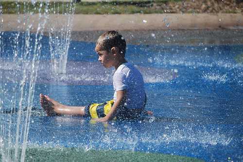 A boy sits at a splash pad in Ryder Park San mateo