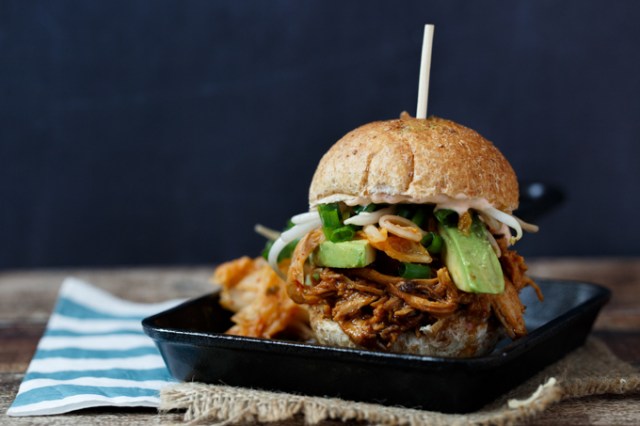 A Korean chicken slider sits on a black plate. It's one of those crock pot recipes that's great for entertaining