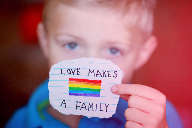 boy holding a rainbow pride paper love makes a family