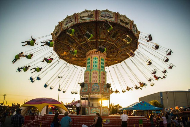 It's evening and the swings are lit up and circling at the Oregon State Fair on Labor Day Weekend