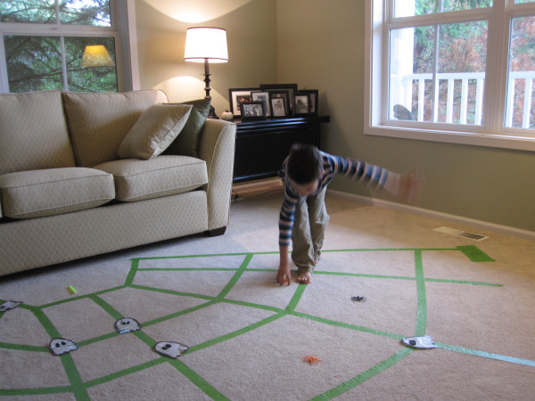 A boy picks up spiders from a web made of tape during this Halloween party game