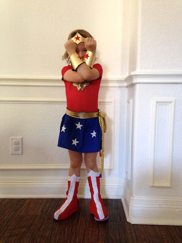 Little girl dressed up like Wonder Woman at a superhero birthday party
