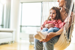 A mother and daughter on a swing indoors