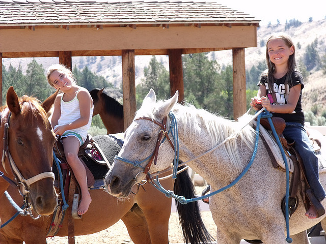 Two girls smiling on horseback