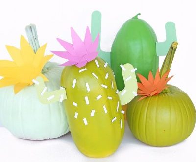 Four green pumpkins are decorated to look like cacti