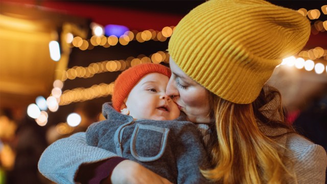 a mom cuddling a bundled up baby during baby's first Christmas