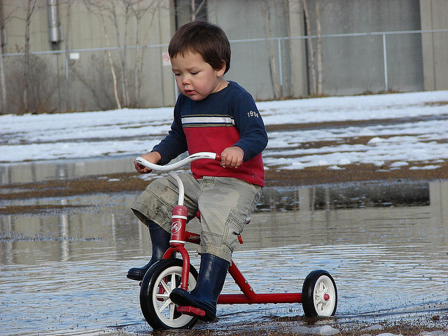 kid on red tricycle 