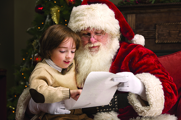Santa looks over a list with a child after taking photos during Santa Cares Day in San Diego