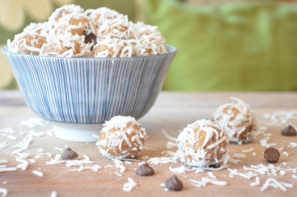 A bowl full of round, powdered no-bake cookies surrounded by a scattering of more powdered cookies