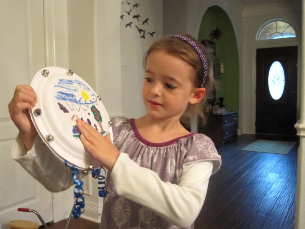 little girl playing a paper plate DIY tambourine