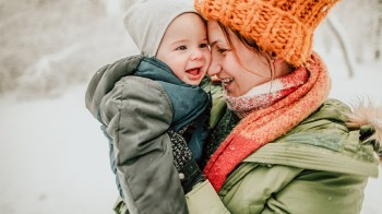 a mom and baby playing in the snow getting ready to do some activities for snow days with baby
