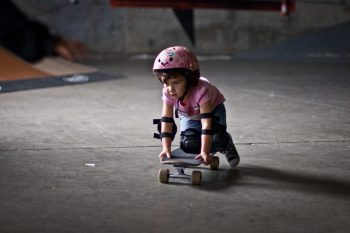 young girl on skateboard with helmet