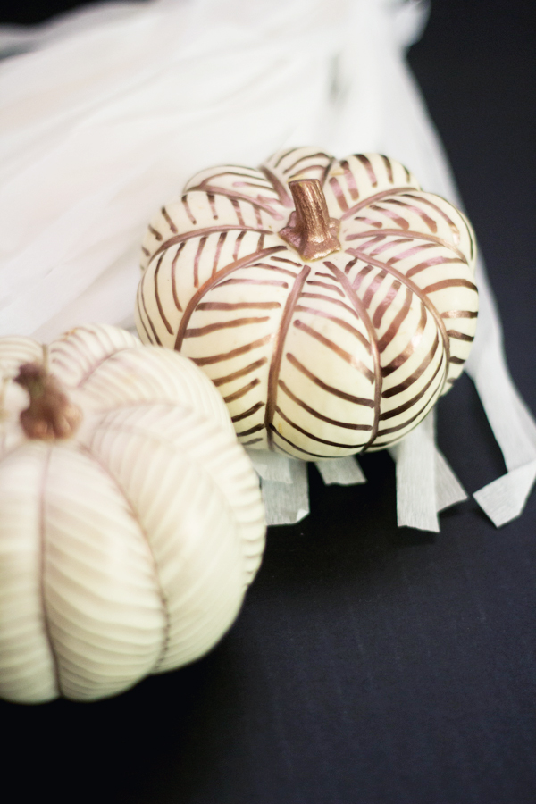Two white pumpkins, one decorated with copper herringbone