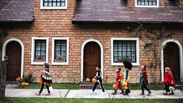 kids in costume trick-or-treating on city sidewalk
