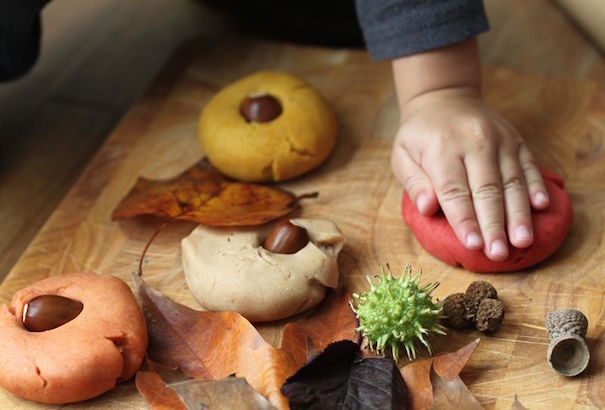 A hand squashes round pieces of homemade pumpkin scented playdough