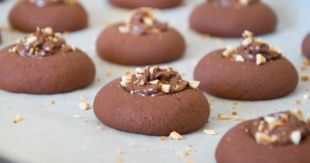 A few rows of brown, round Christmas cookies that are made with nutella and topped with nuts