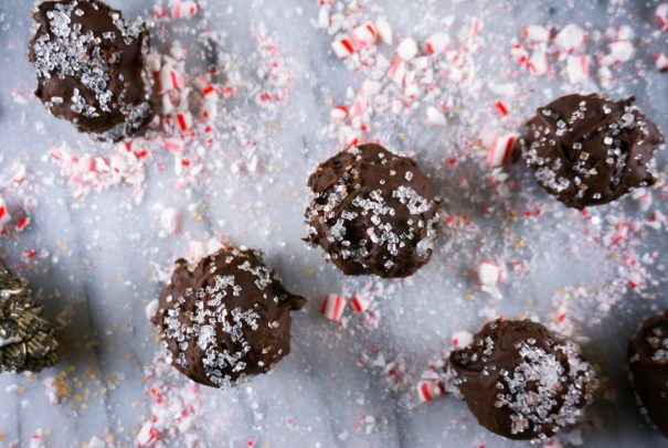 Several oreo bonbon cookie balls are dusted in candy cane pieces