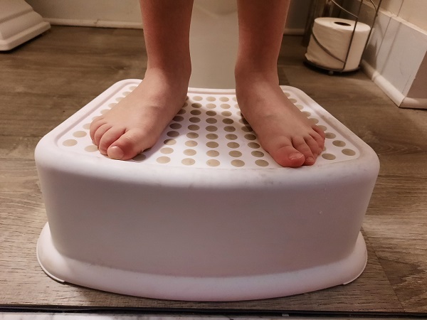 a kid standing on a stool during potty training