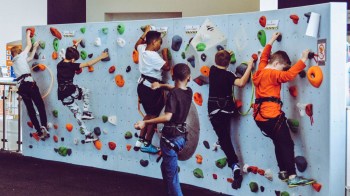 Kids climb a rock wall at a portland climbing gym