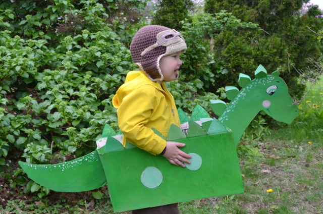 A boy is dressed as a dragon for Halloween using a cardboard box
