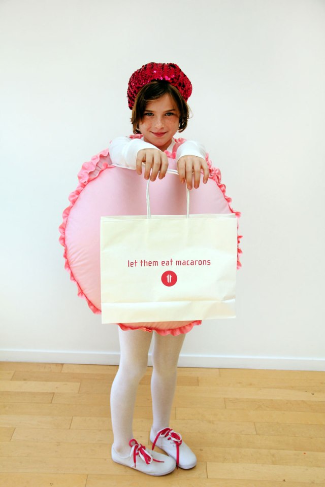 A girl is dressed up in a box for Halloween to look like a pink macron