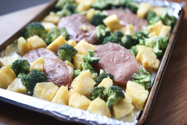 A sheet pan dinner with pork chops, roasted broccoli and fresh pineapple chunks