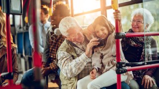 grandparents with child looking at camera on city bus