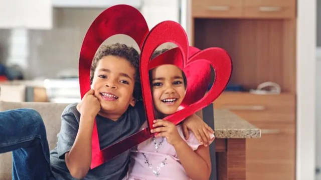 two kids posing with hearts around their heads for a story on valentine's day traditions