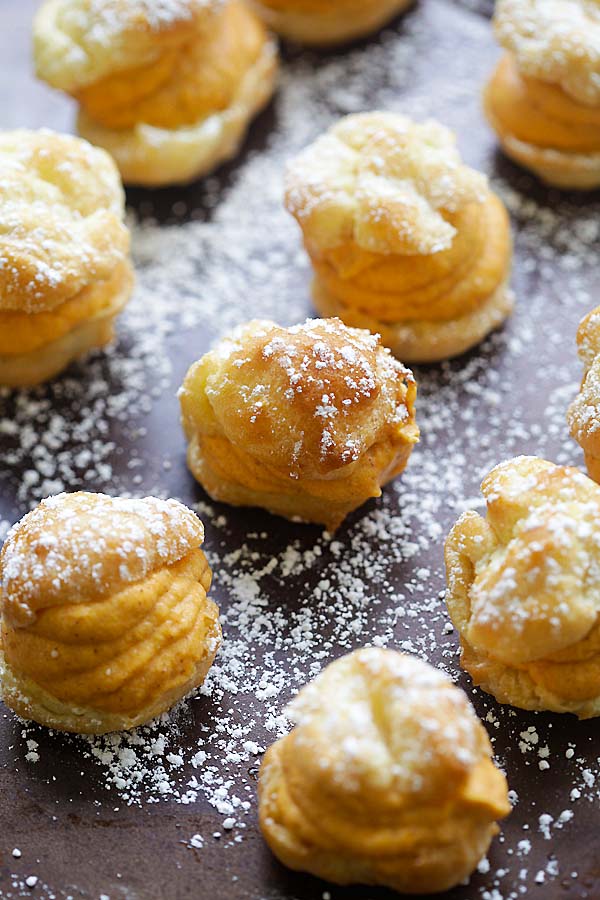 A platter of light and airy choux puff pastry, filled with a sweet pumpkin cream and dusted in powdered sugar
