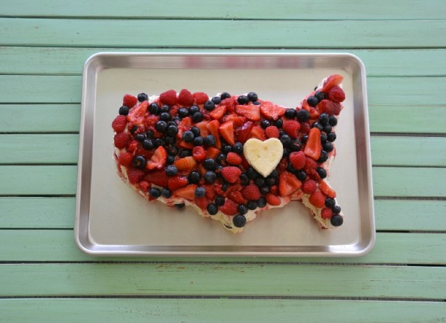 A cake in the shape of the USA and covered in sliced fruit for memorial Day