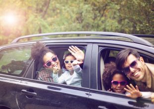 Family waves from the car during a family activity road trip