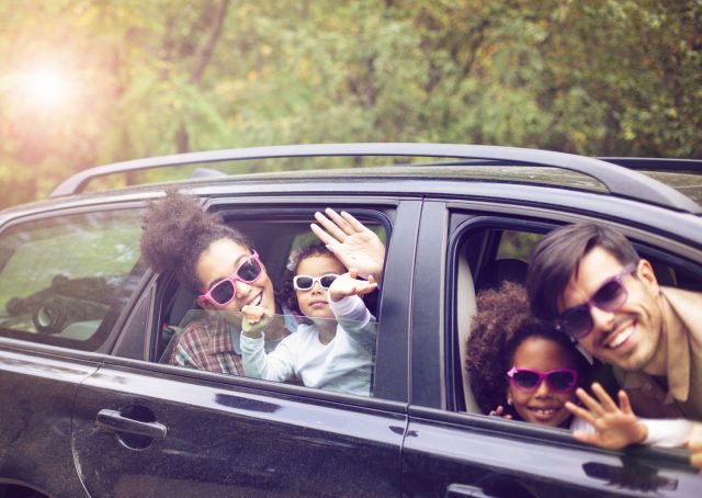 Family waves from the car during a family activity road trip