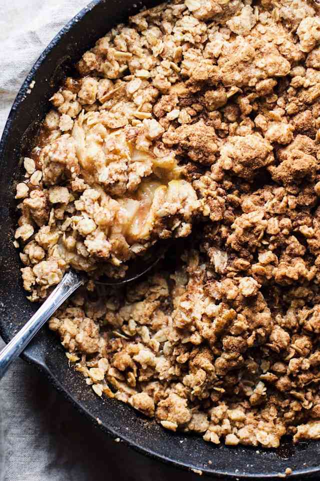 A cinnamon apple crumble with a serving spoon in it ready to dish out this Thanksgiving dessert