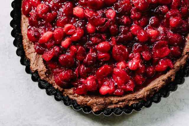 A cranberry tart with chocolate cookie crust is covered with mascarpone-flavored with cocoa, including a cranberry compote to top it off