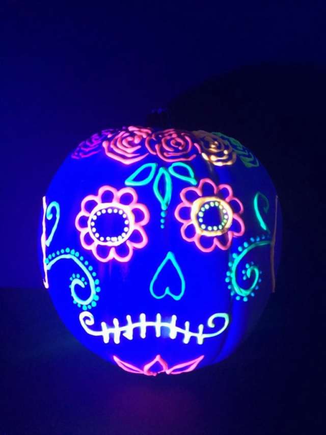 A glowing pink, blue and white skull pumpkin as a no-carve pumpkin decorating idea