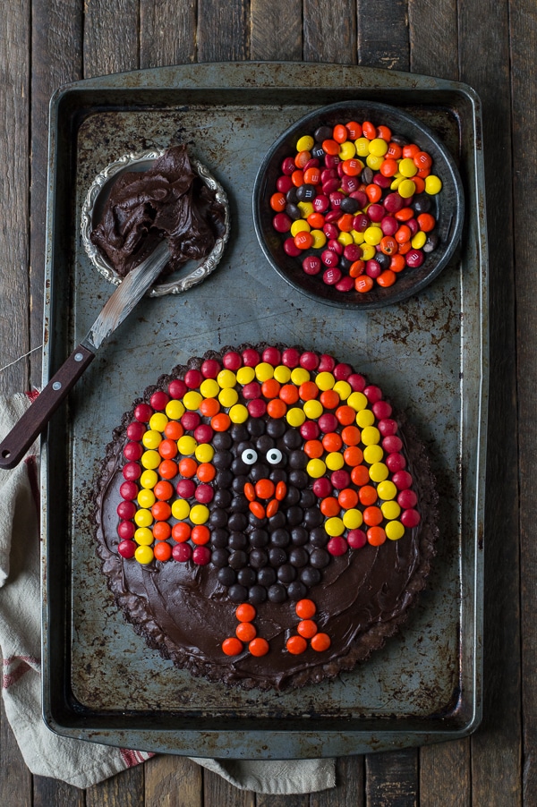 A sweet turkey tart is covered in M&Ms, which also sit in a bowl nearby, for a colorful fall treat that isn't pie