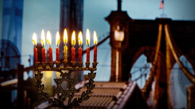 A Hanukkah menorah fully lit with NYC's Brooklyn Bridge in background