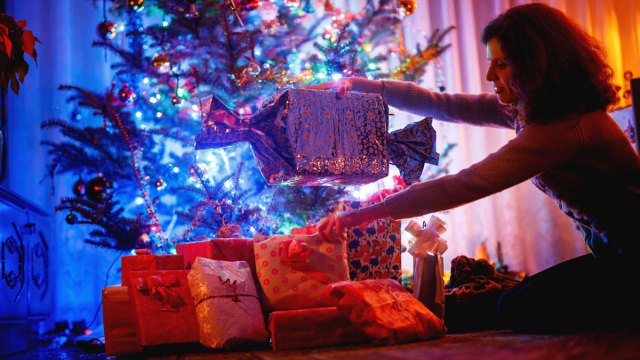 a mother arranging gifts under the Christmas tree