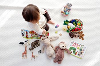 a baby sitting on the floor surrounded by a variety of different toys