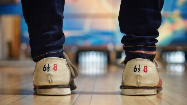 a person stands at a bowling lane ready to roll the ball