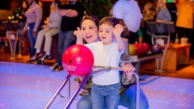 at a portland bowling alley, a mom and son bowl with a ramp