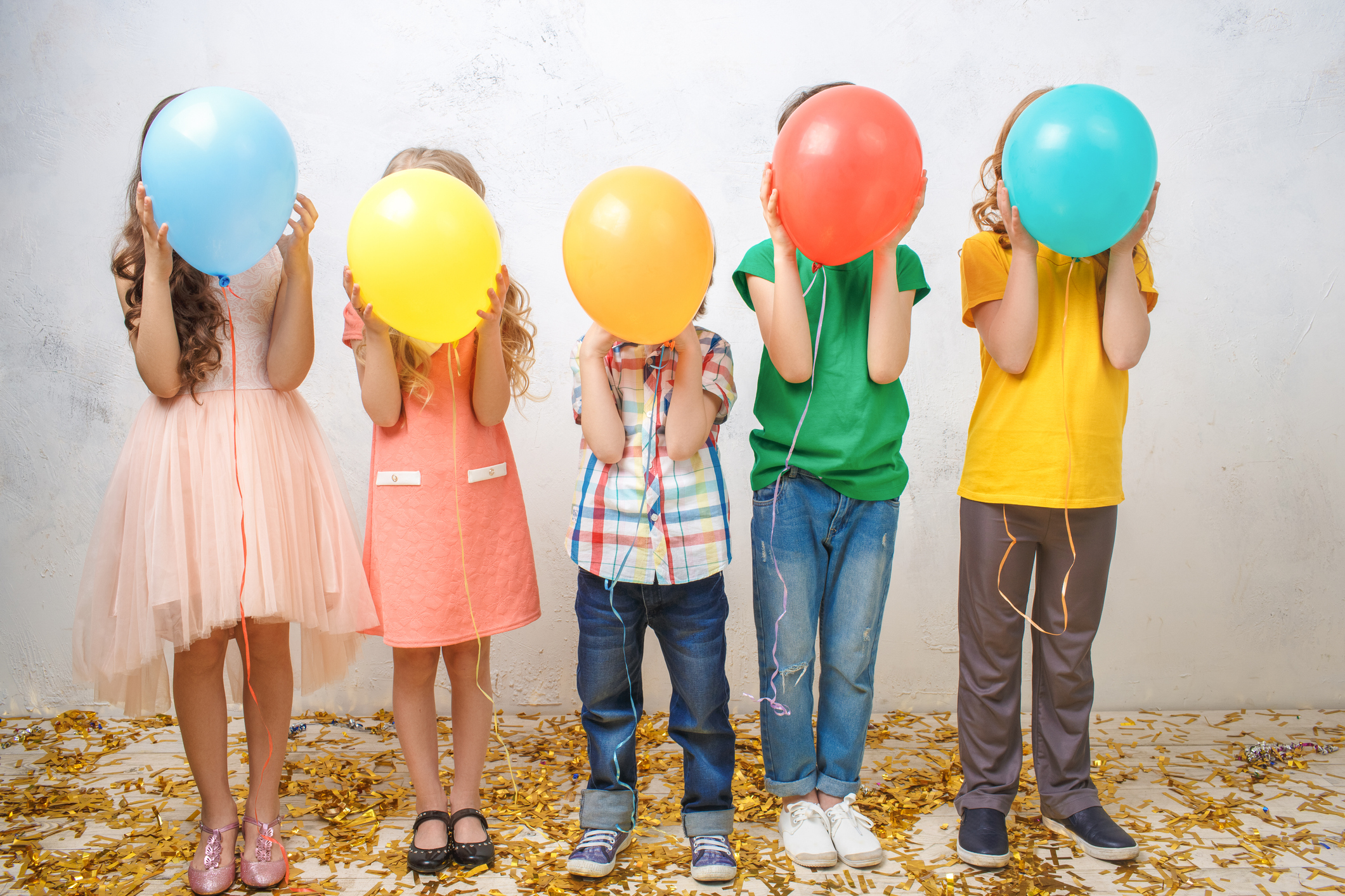 Five kids hold balloons to their faces as they prepare to play a musical game