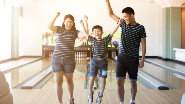 a boy and his parents jump for joy in a bowling seattle alley