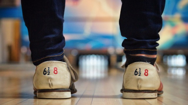 close up of numbered bowling shoes with pins and a lane faded in the background