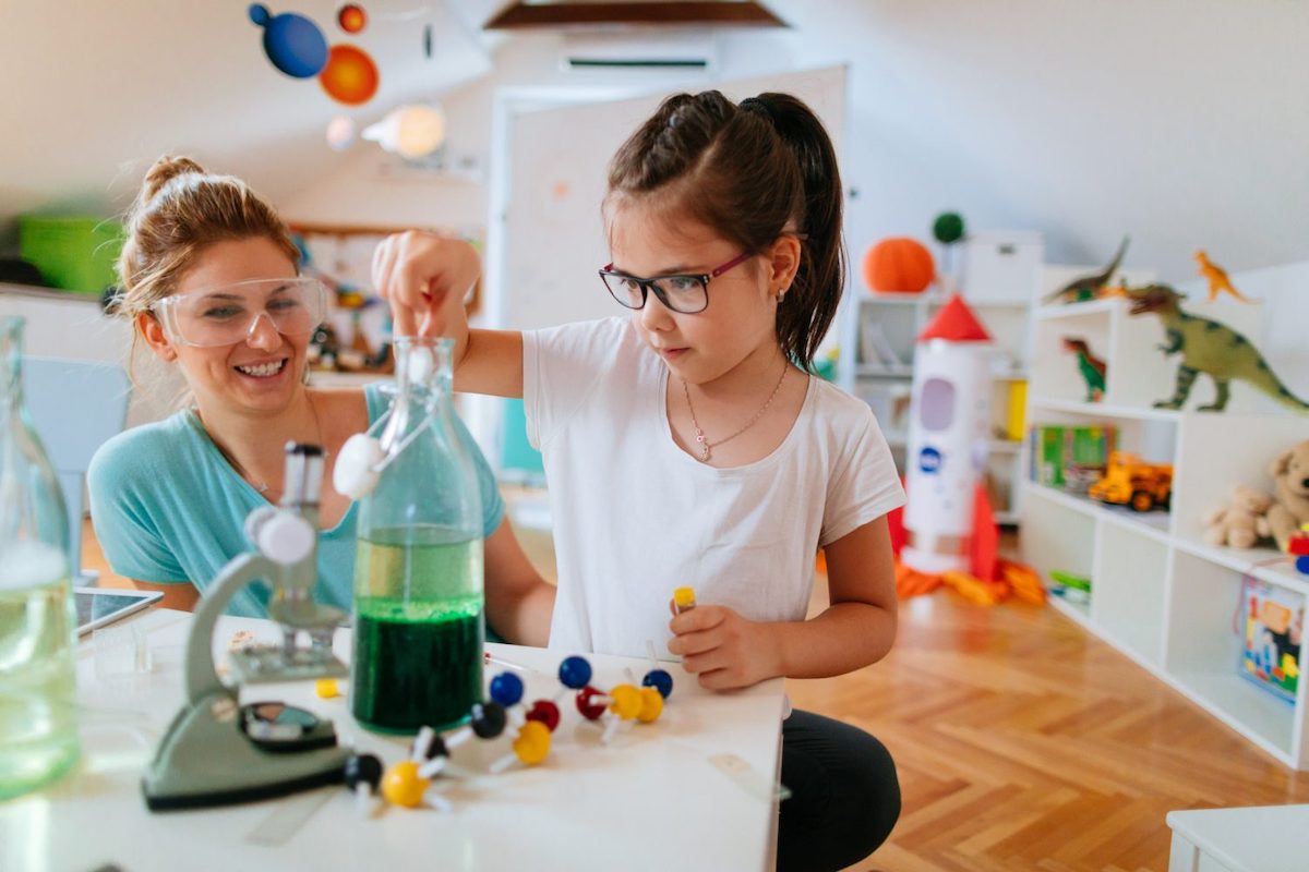 a girl does an experiment with safey goggles while her mom looks on